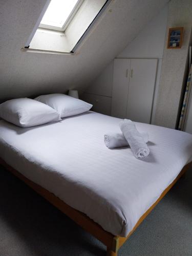 une chambre avec un lit avec des draps blancs et des oreillers dans l'établissement Appartement vue mer exceptionnelle à 100m très belle plage, à Saint-Gildas-de-Rhuys