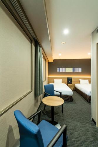 a hotel room with two beds and a table and chairs at Hakata Nakasu Washington Hotel Plaza in Fukuoka