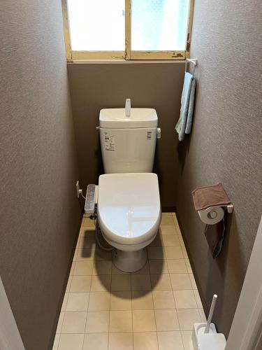 a small bathroom with a toilet with a window at Otaru Eminabackpackers in Otaru