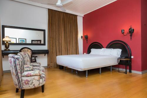 a bedroom with a bed and a chair and a mirror at B&B HOTEL Sado Setúbal in Setúbal