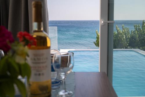 a bottle of wine sitting on a table next to a pool at Kontemare Seascape in Koumeika