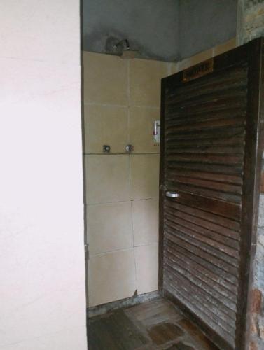 a bathroom with a shower with a metal door at The Last Resort - Safari Tent in Ghumthāng