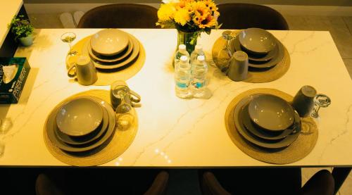 a table with plates and dishes and a vase of flowers at Axon Residence KLCC - KL HOME in Kuala Lumpur