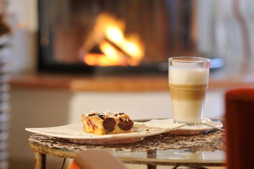 a plate with a piece of cake and a glass of milk at Romantik Alpenhotel Waxenstein in Grainau