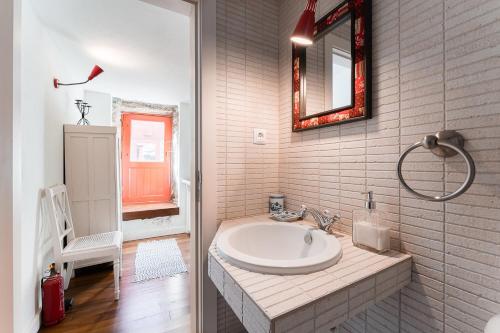 a white bathroom with a sink and a mirror at GuestReady - Quintinha casas do jardim 2 in Arcos de Valdevez