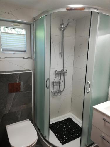 a shower with a glass door in a bathroom at Domki Mantras in Swarzewo