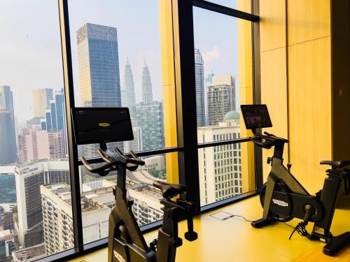 a gym with treadmills and ellipticals in front of a window at Axon Residence KLCC - KL HOME in Kuala Lumpur
