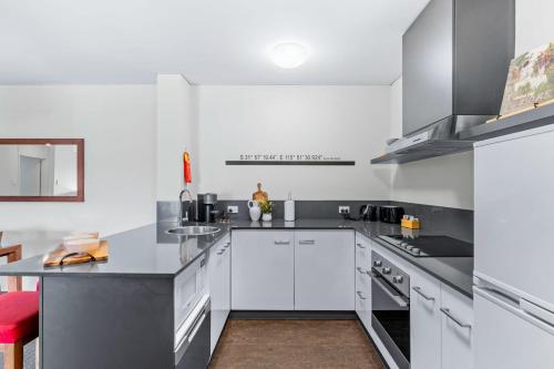a kitchen with white cabinets and a red chair at Hay Street CBD Apartment close to Swan River in Perth