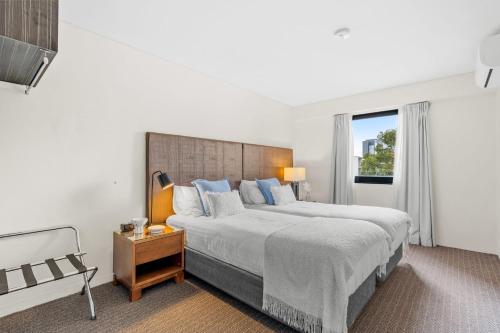 a white bedroom with a large bed and a window at Hay Street CBD Apartment close to Swan River in Perth