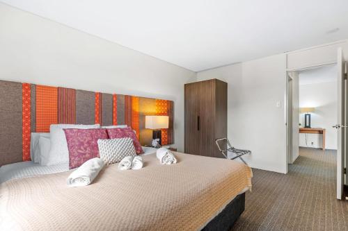 a bedroom with a large bed with pink pillows at Hay Street CBD Apartment close to Swan River in Perth