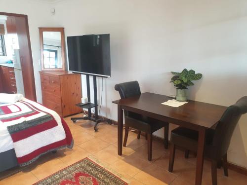 een eetkamer met een tafel en een televisie bij Cape Cottage in Kaapstad