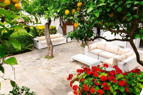 a patio with two white couches and red flowers at Villa Elena by MyVillaCollection in Capri