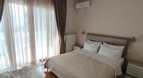 a bedroom with a bed with white pillows and windows at Η πέρλα της λίμνης/ The lake's pearl in Ioannina