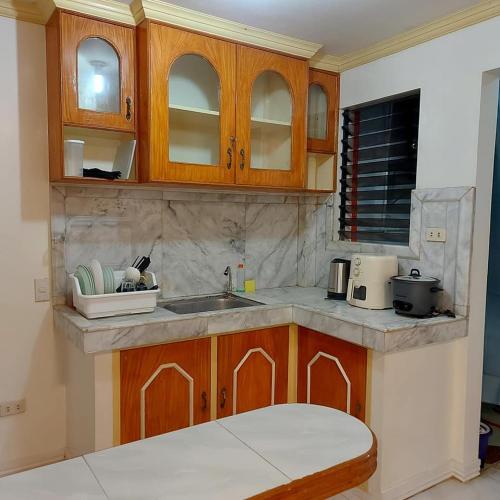 a kitchen with wooden cabinets and a sink at TST Transient Home - WiFi Access, Kitchenette, Private Bathroom in Romblon
