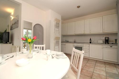 a kitchen with a white table with flowers in a vase at Ostseeresidenz Appartements Wischuer Fewo 11 in Wischuer