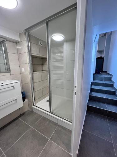 a bathroom with a walk in shower next to a staircase at Studio Cozy proche aéroport CDG in Claye-Souilly