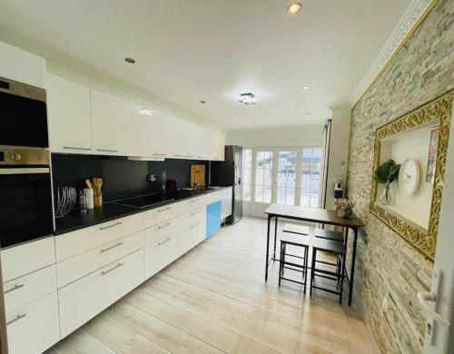 une cuisine avec des armoires blanches et une table à l'intérieur dans l'établissement Maison Familiale avec Jardin, à Ozoir-la-Ferrière