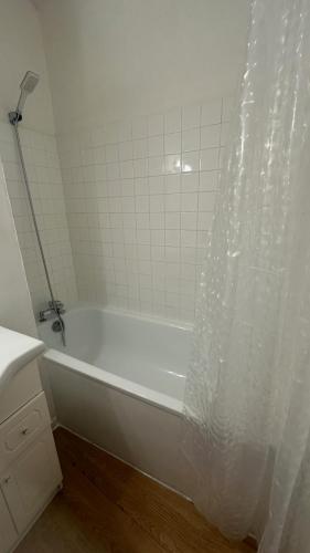 La salle de bains est pourvue d'une baignoire blanche avec rideau de douche. dans l'établissement Gîte au cœur de la ville ancienne, à Terrasson