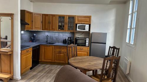 una cucina con armadi in legno, tavolo in legno e sidro da tavolo di Gîte au cœur de la ville ancienne a Terrasson-Lavilledieu