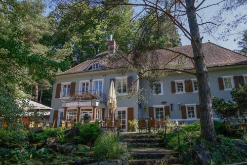 einen Blick auf ein weißes Haus mit Bäumen in der Unterkunft Hotel und Restaurant Halbinsel in Blieskastel