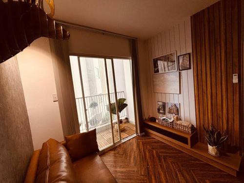 sala de estar con sofá de cuero y ventana grande en Daisy Home Luxury, en Ấp Mỹ Hòa
