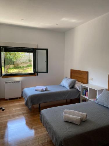 a bedroom with two beds and a window at Carballeira in Moraña