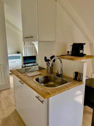 une cuisine avec un évier et un ordinateur portable sur un comptoir dans l'établissement Le Paris Thabor Centre-ville, à Rennes