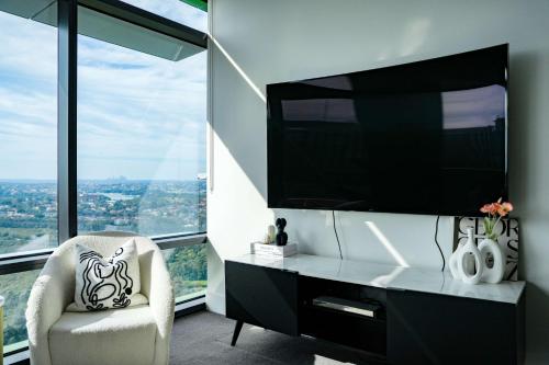 a living room with a tv and a chair at High-Rise with Park View in Sydney Olympic Park in Sydney