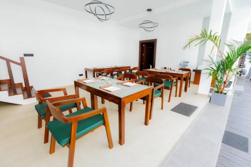 a dining room with wooden tables and green chairs at KADUPUL By Serenity in Negombo