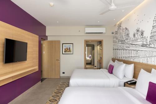 a hotel room with two beds and a tv at Lilac Kumbakonam in Kumbakonam