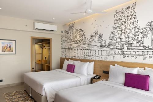 two beds in a hotel room with a drawing on the wall at Lilac Kumbakonam in Kumbakonam