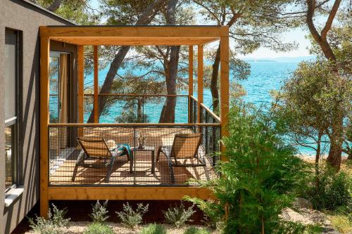 a gazebo with two chairs and a table on a porch at Pine Beach Mobile homes all inclusive in Pakoštane