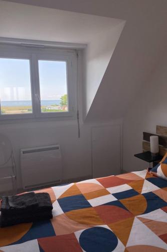 une chambre avec un lit coloré avec une fenêtre dans l'établissement Maison face à l'océan, à Sarzeau