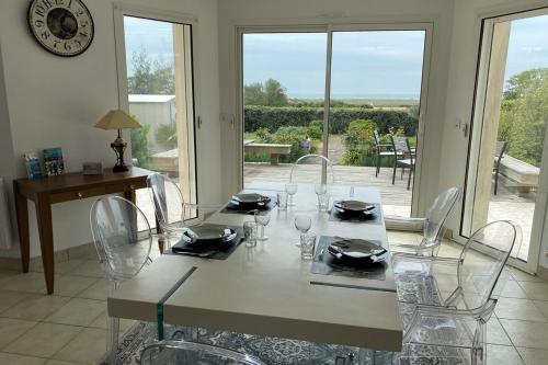 une salle à manger avec une table, des chaises et une horloge dans l'établissement Maison face à l'océan, à Sarzeau