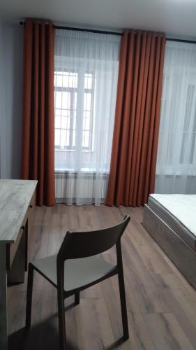 a room with a chair and a bed and curtains at Fishel in Odesa