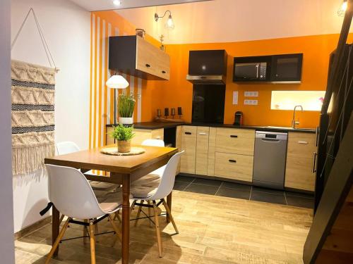 - une cuisine avec une table en bois et des chaises blanches dans l'établissement Maison de Ville Nid Cosy, à Chavanay