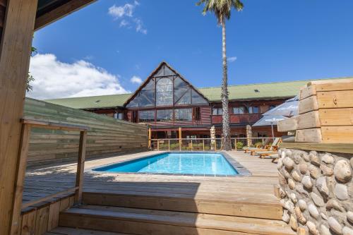 a house with a pool and a palm tree at Knysna Log-Inn Hotel in Knysna