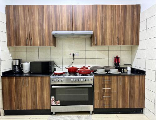 a kitchen with a stove and wooden cabinets at Homely 3-bedroom Apartment at Victoria Place in Dar es Salaam