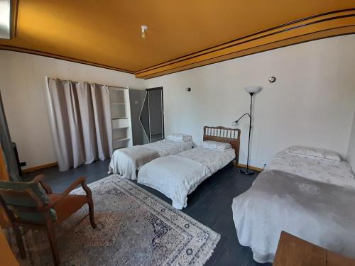 Cette chambre comprend trois lits et une chaise. dans l'établissement Gîte du RELAI du Château - Parc Oriental - Puy du Fou, à La Tourlandry