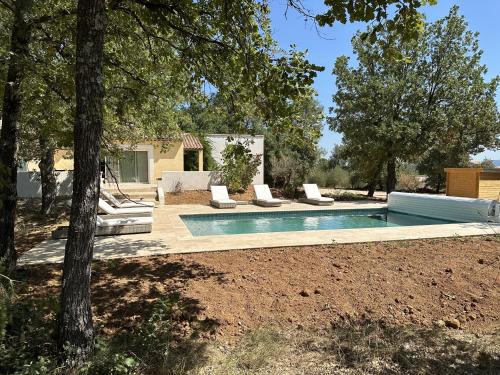 une piscine avec des chaises longues à côté d'une maison dans l'établissement Sous les oliviers, Villa entière 6 personnes, climatisée, piscine chauffée, à Saint-Maximin-la-Sainte-Baume