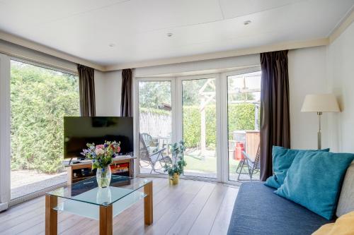 a living room with a blue couch and a tv at GREAT STAY - NATURE - Outside HOTTUB en SAUNA in Voorthuizen