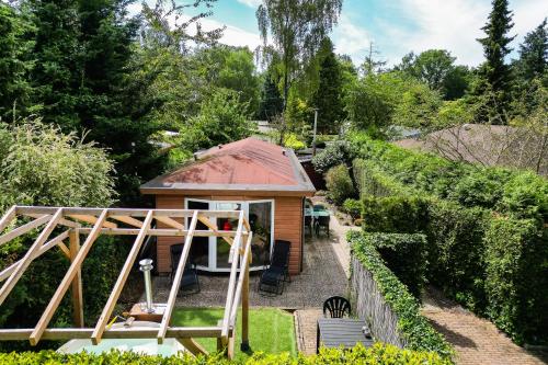 a small cabin with a red roof in a garden at GREAT STAY - NATURE - Outside HOTTUB en SAUNA in Voorthuizen
