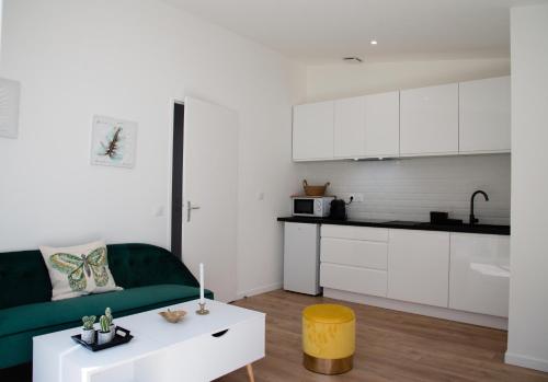 un salon avec un canapé vert et une cuisine dans l'établissement Charment T2 avec extérieur à 200m du Tram C, à Le Bouscat
