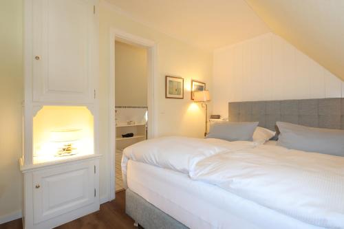 a bedroom with a white bed with a light on it at Boutiquehotel Seiler Hof Keitum in Keitum