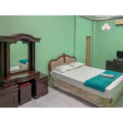 a bedroom with a bed and a dresser and a mirror at Afiat Hotel Maros Makassar RedPartner in Makassar