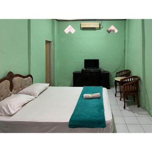 a bedroom with a bed with a chair and a desk at Afiat Hotel Maros Makassar RedPartner in Makassar