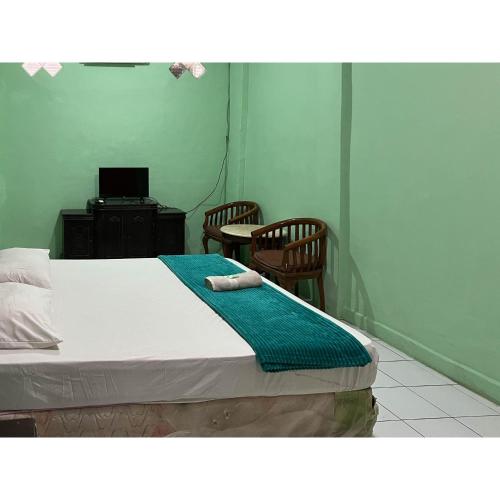a room with a bed with two chairs and a desk at Afiat Hotel Maros Makassar RedPartner in Makassar