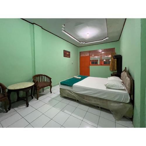 a bedroom with a bed and a table and chairs at Afiat Hotel Maros Makassar RedPartner in Makassar
