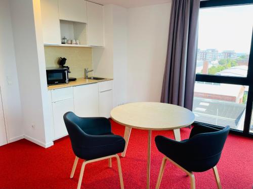 a room with a table and two chairs and a kitchen at havenhostel Cuxhaven in Cuxhaven