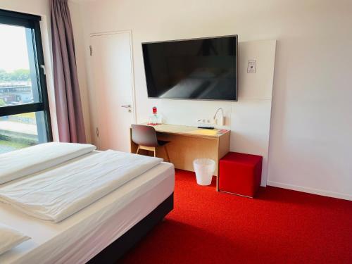 a hotel room with a bed and a desk and a tv at havenhostel Cuxhaven in Cuxhaven